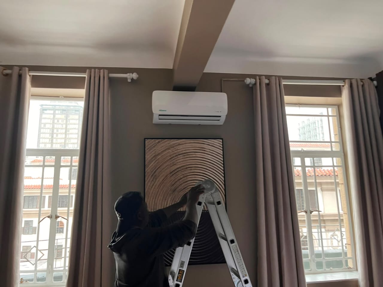 Technician installing a wall-mounted split air conditioner in a modern living room